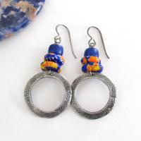 These handcrafted earrings feature silver pewter circle hoops with a hand stamped texture accented with colorful African glass beads and navy blue glass beads. They have an earthy, boho style and are lightweight and comfortable to wear.  MEASUREMENTS: Total length 2" from top of gray silver niobium (hypoallergenic) ear wires and 1” at widest point. The circles were created out of solid lead-free pewter; hand stamped and oxidized; and signed on the back with my initials
