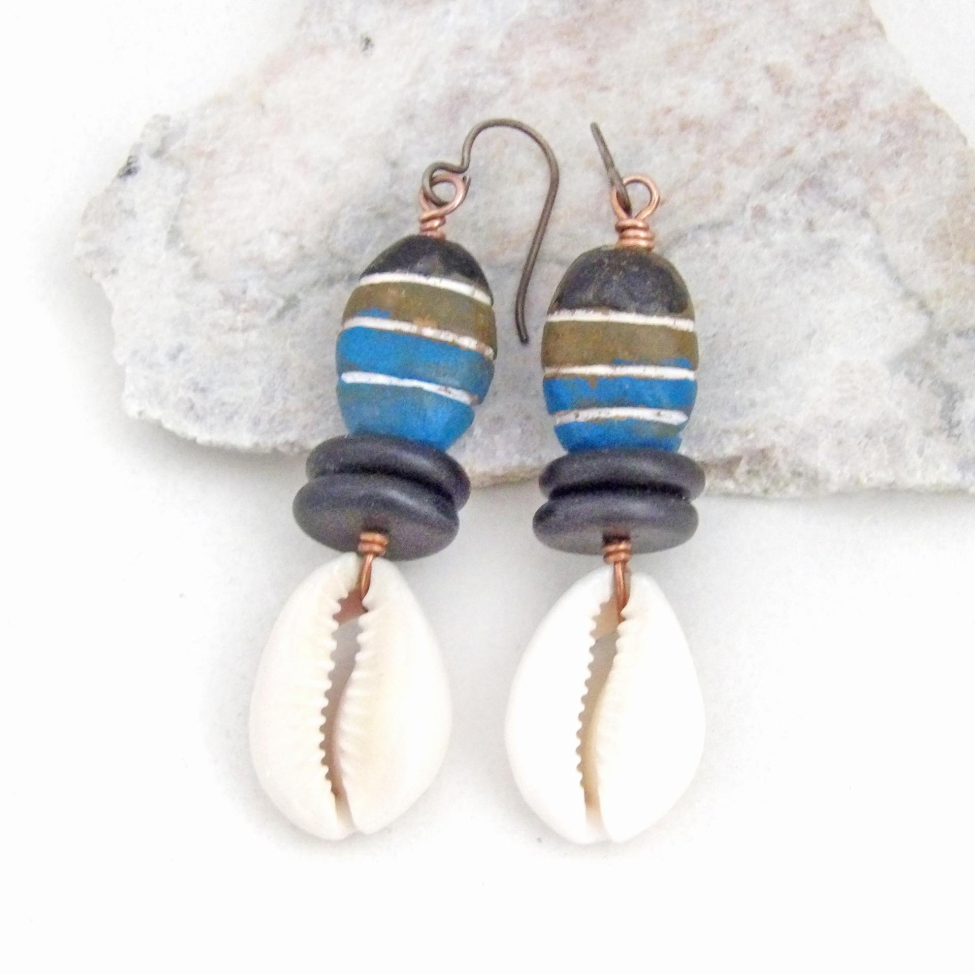 These handmade earrings feature colorful blue, cocoa brown and black painted wood beads accented with cowrie shell dangles and black jasper beads. They have a bold, ethnic tribal flair and will make a unique statement.