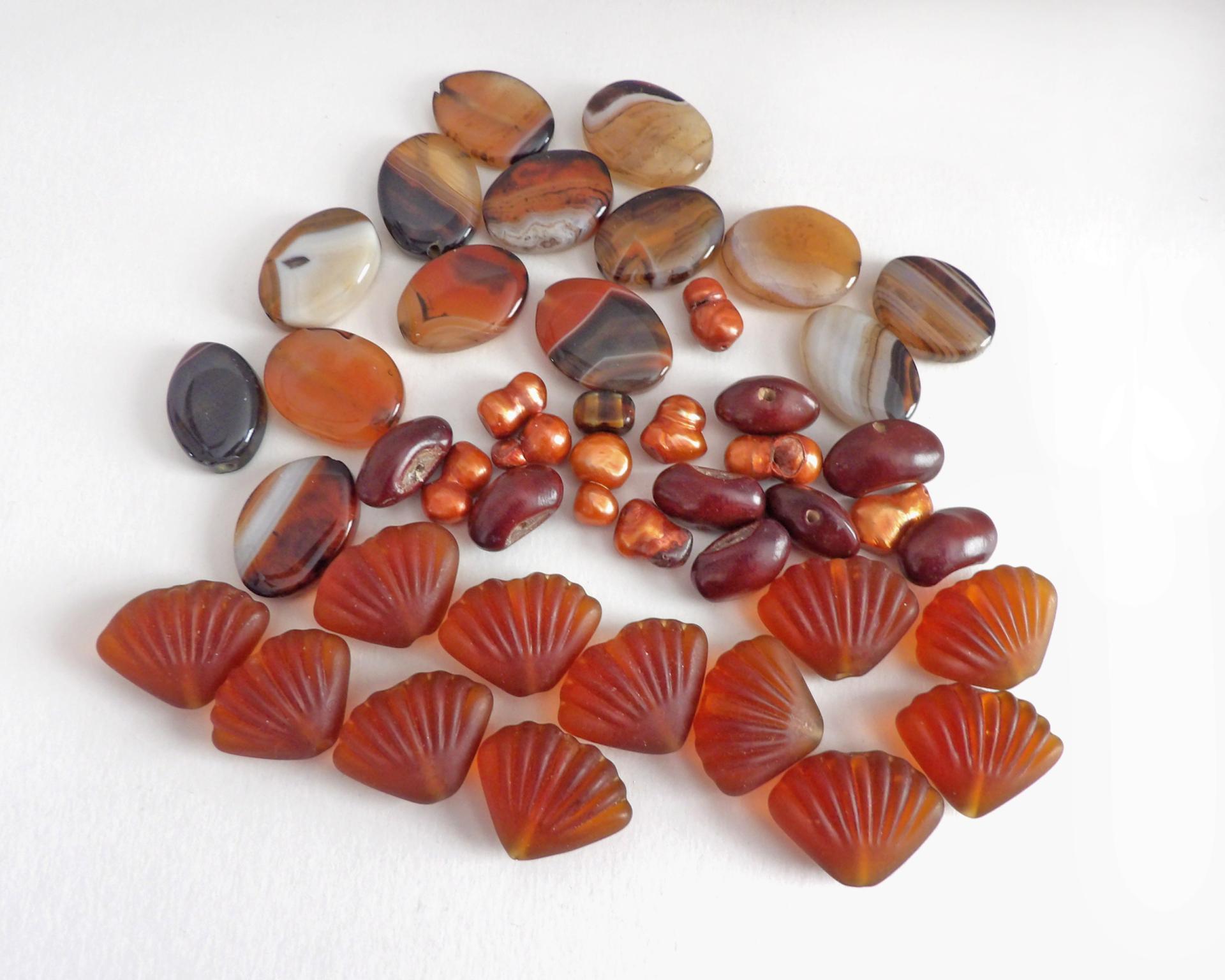 Mixed bead lot for jewelry making / beading / craft supply.  Lot consists of 14 pieces of oval-shaped banded agate beads (black orange white tones with various matrix patterns). Measures approximately 7/8" to 1" in length and 3/4" in width - drilled top to bottom. 12 pieces of burnt orange seashell shaped beads. Measures approximately 1" at widest point and 3/4" in length - drilled top to bottom 9 bright orange organically shaped freshwater pearl beads - drilled 8 dark reddish-brown dried bean beads