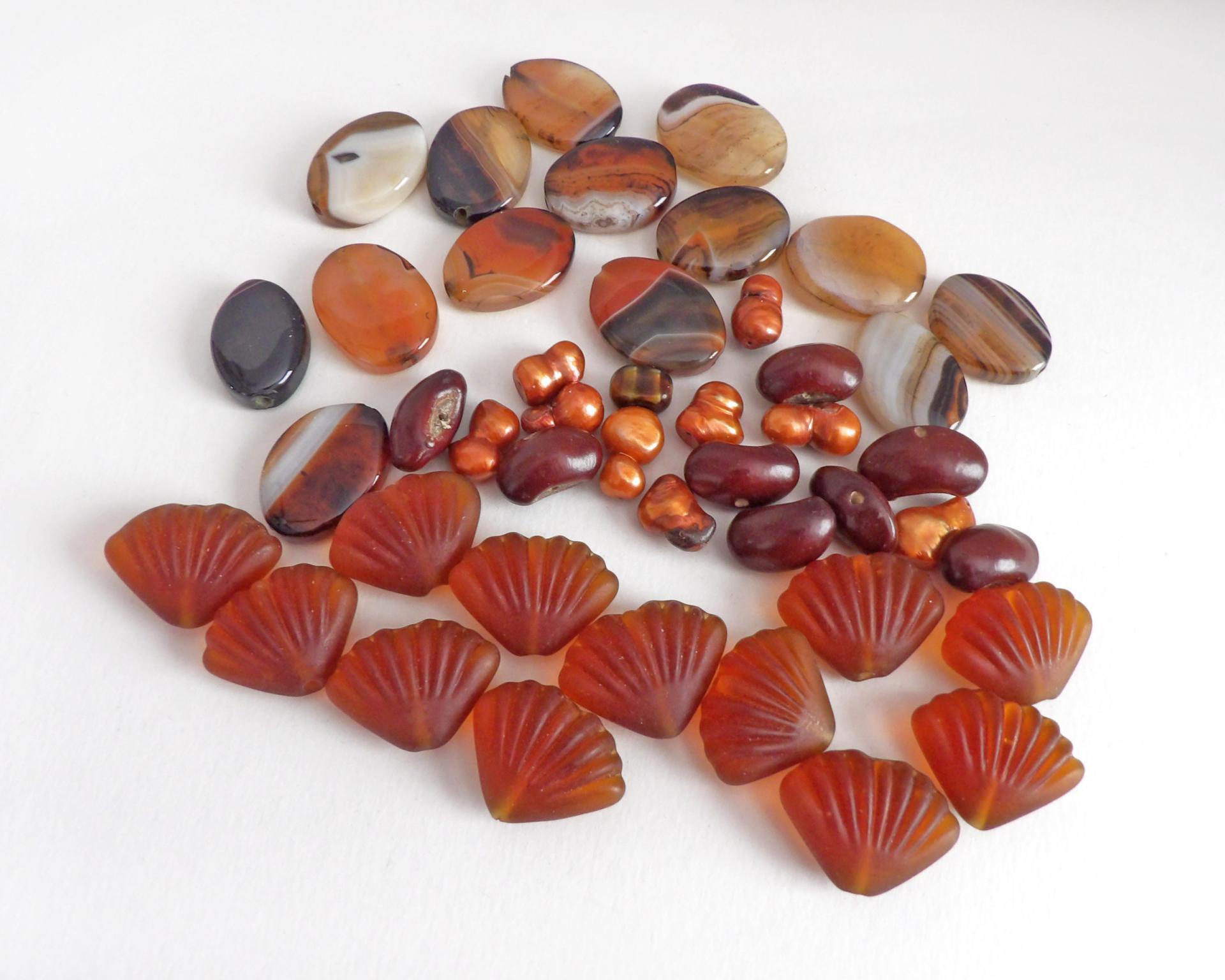 Mixed bead lot for jewelry making / beading / craft supply.  Lot consists of 14 pieces of oval-shaped banded agate beads (black orange white tones with various matrix patterns). Measures approximately 7/8" to 1" in length and 3/4" in width - drilled top to bottom. 12 pieces of burnt orange seashell shaped beads. Measures approximately 1" at widest point and 3/4" in length - drilled top to bottom 9 bright orange organically shaped freshwater pearl beads - drilled 8 dark reddish-brown dried bean beads