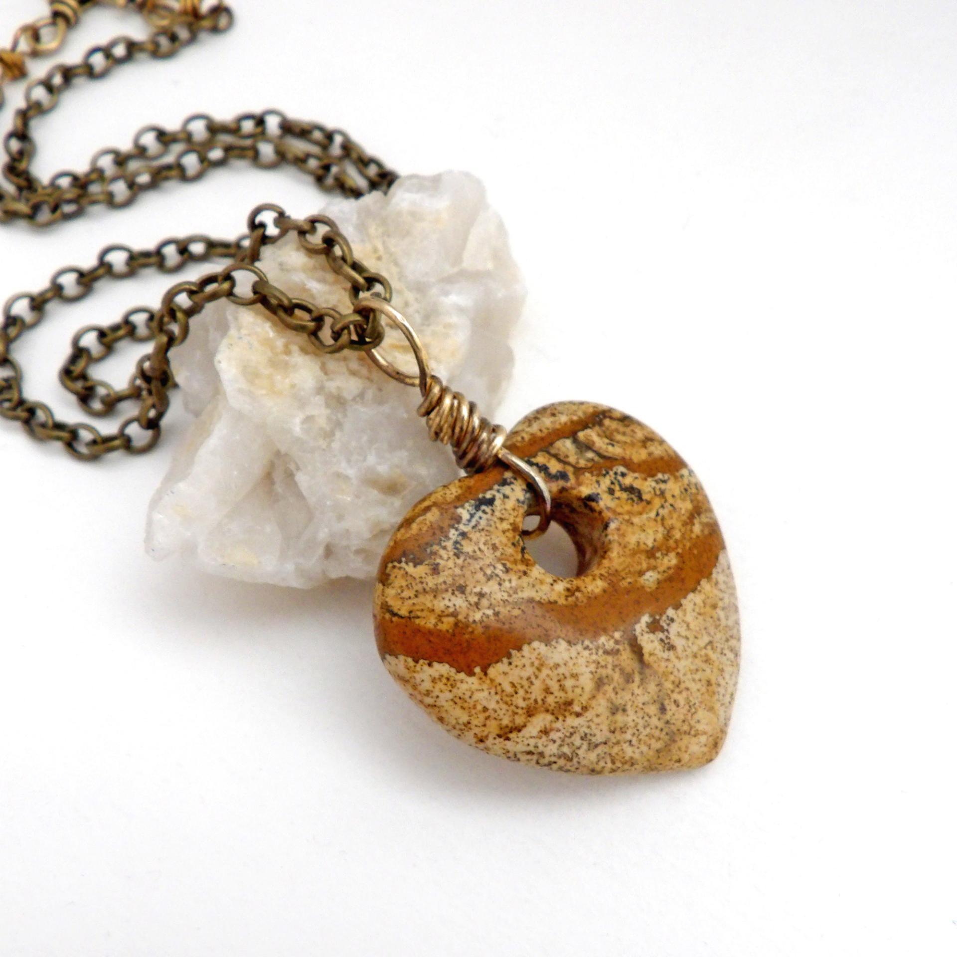 This handcrafted pendant necklace has a simplistic earthy charm. It features a natural picture jasper gemstone carved into a heart shape. It's wrapped in antiqued brass wire and comes on an 18" antiqued brass chain. The stone has a natural pattern with markings of tan, mocha brown and black. Makes a great gift to tell someone "I love you" - or a nice addition to your own jewelry collection.