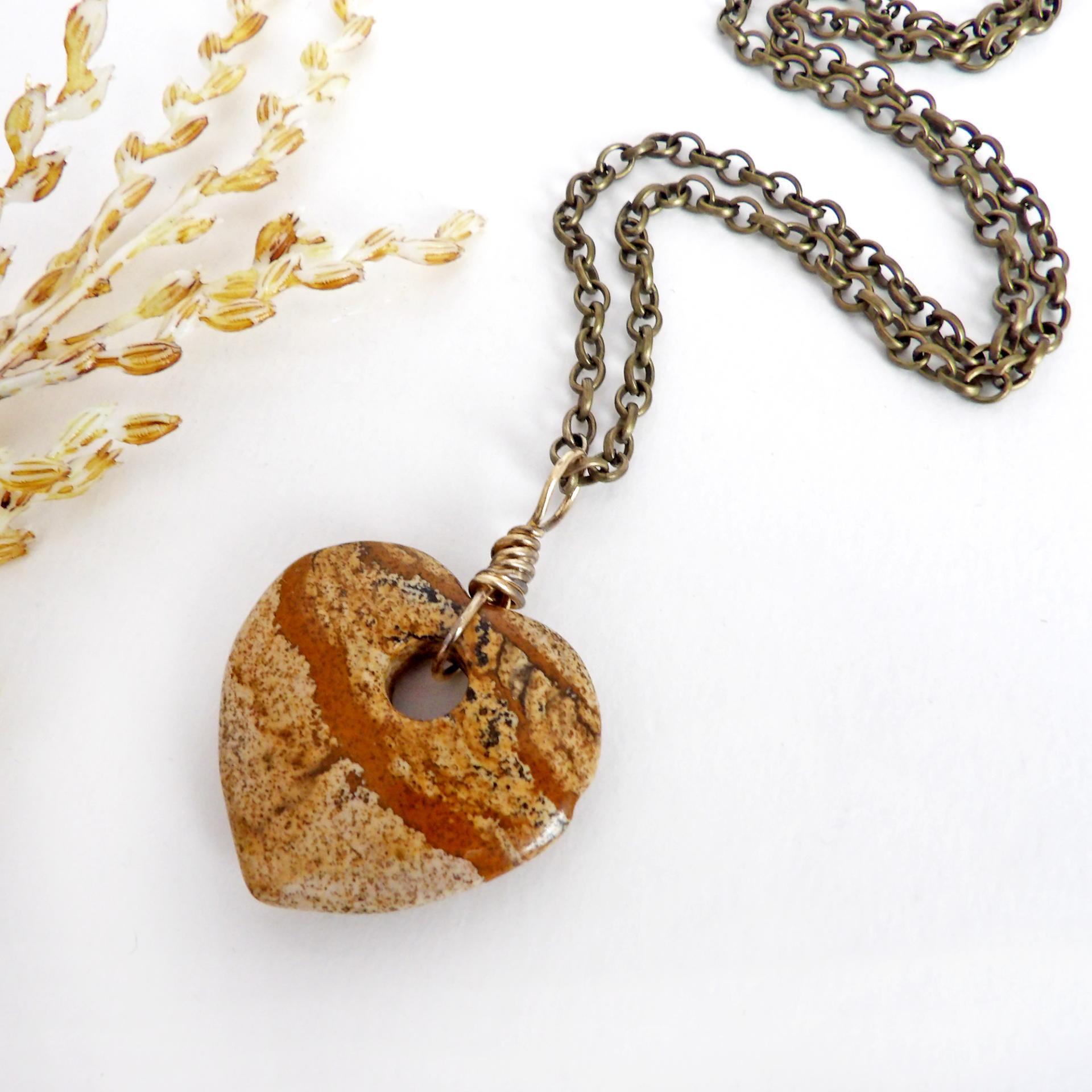 This handcrafted pendant necklace has a simplistic earthy charm. It features a natural picture jasper gemstone carved into a heart shape. It's wrapped in antiqued brass wire and comes on an 18" antiqued brass chain. The stone has a natural pattern with markings of tan, mocha brown and black. Makes a great gift to tell someone "I love you" - or a nice addition to your own jewelry collection.