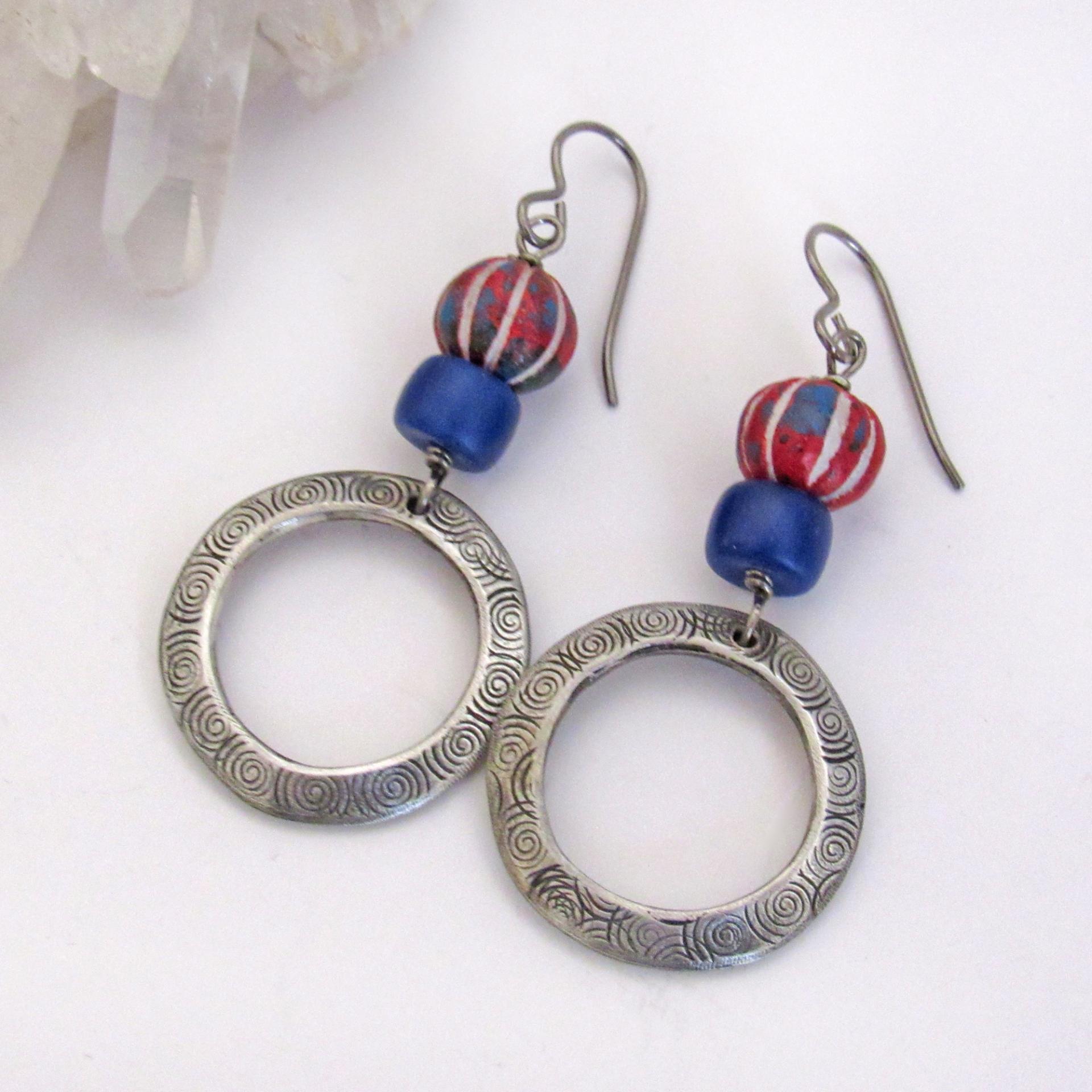 These handcrafted earrings feature silver pewter circle hoops with a hand stamped texture accented with red, white and blue carved clay beads and navy blue glass beads. They have an earthy, boho style and are lightweight and comfortable to wear. Great USA colors for a July 4th celebration. 