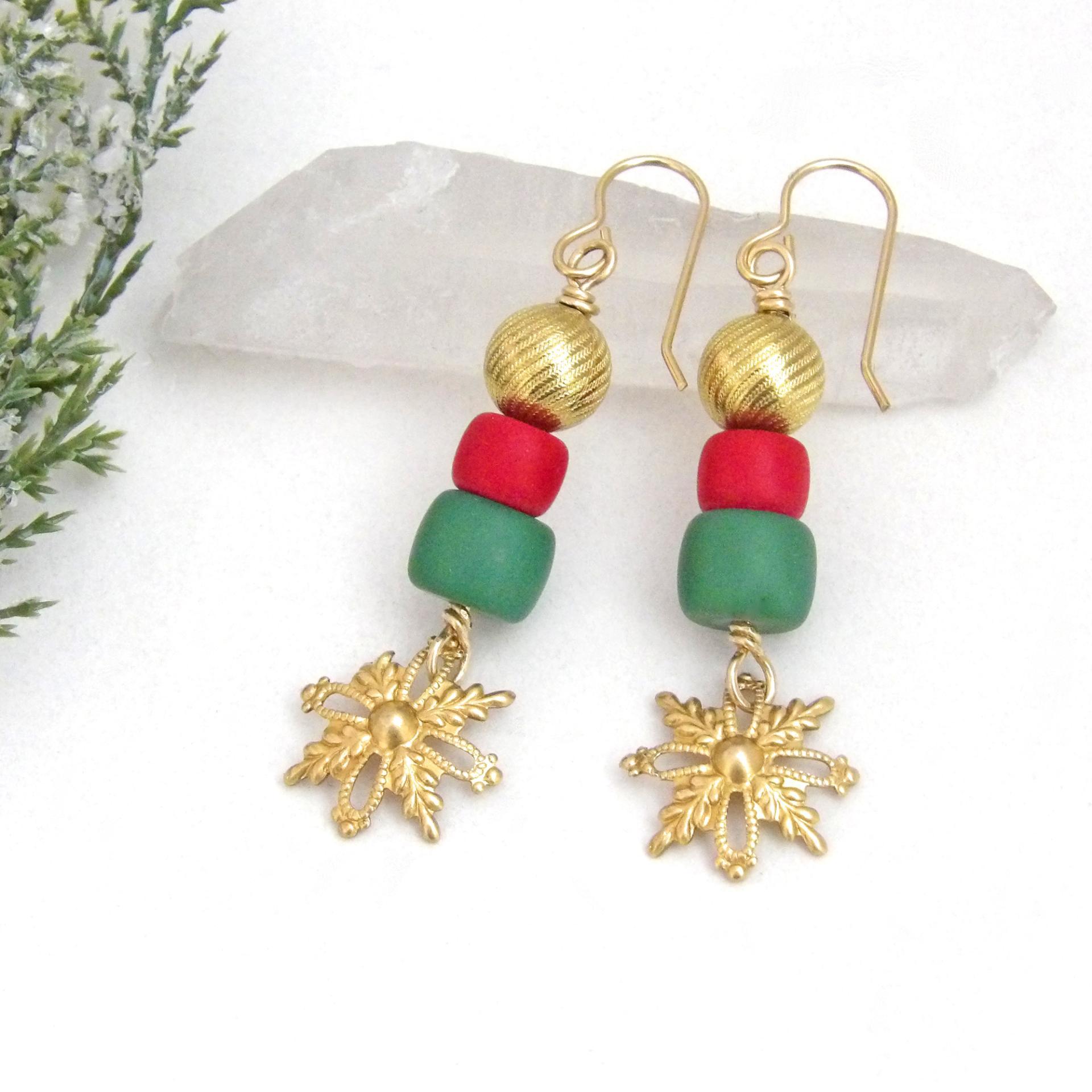 Full of elegant holiday charm, these handmade dangle earrings feature gold brass snowflake filigree charms accented with red and green glass beads topped off with textured gold brass beads. They have a modern charm with a boho chic style that's perfect for the holiday and Christmas season. They'll make a great gift for someone that loves handmade jewelry - or a nice addition to your own wardrobe.